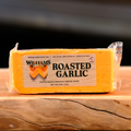 A packaged block of William's Roasted Garlic cheese on a wooden surface.