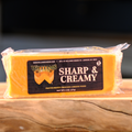 Packaged block 'William's Sharp & Creamy' cheese on a wooden surface.