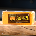 A packaged block of William's Smoked Cheddar Cheese on a wooden surface.