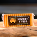 A packaged block of William's Smoked Swiss Cheese placed on a wooden surface.